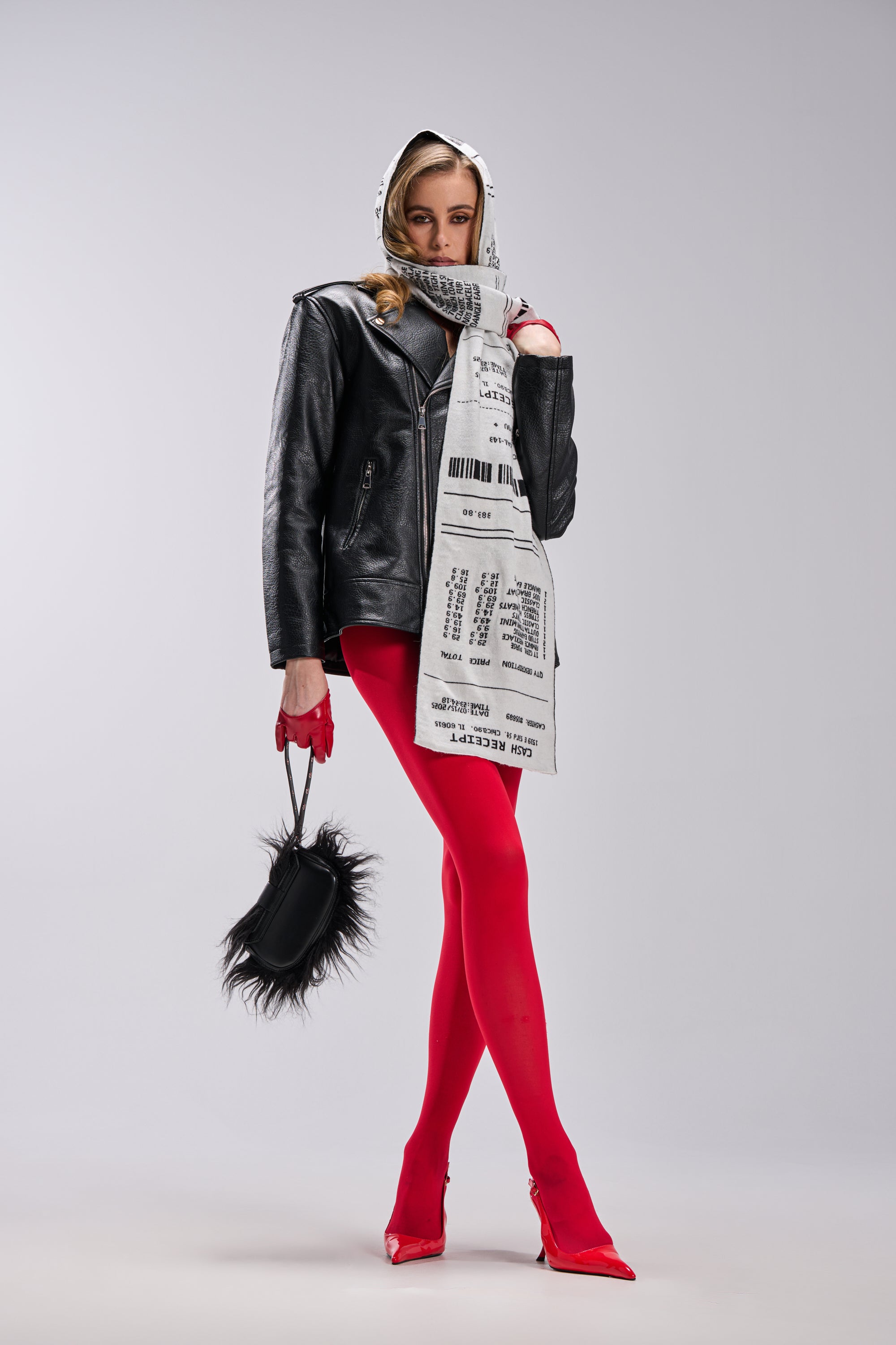 A stylish woman poses in bright red tights, red heels, a black leather jacket, and the CHECK THE RECEIPT SCARF—a chic cold-weather accessory—while holding a furry black handbag against a plain light background. 2