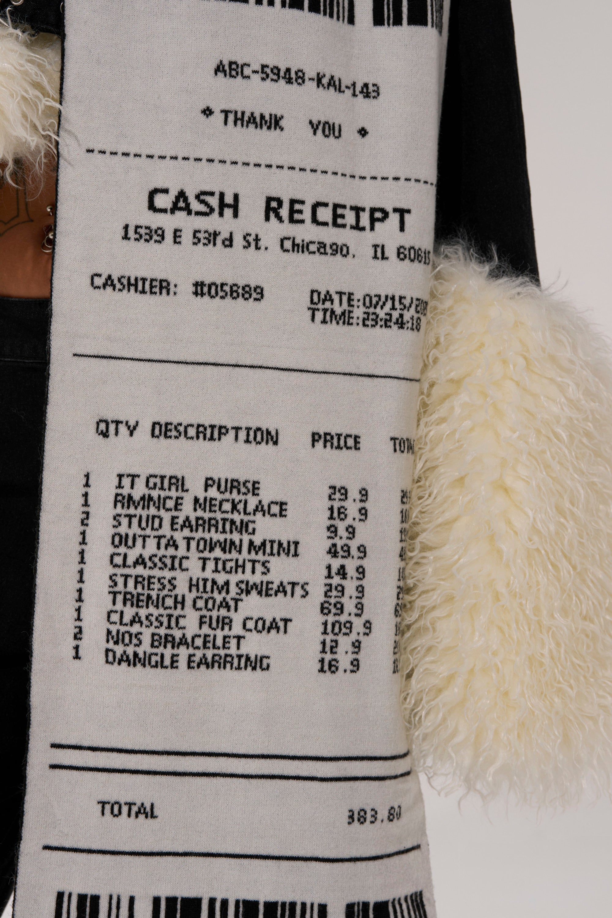 The CHECK THE RECEIPT SCARF is a wool-blend knit scarf designed like a printed cash receipt of fashion items and prices—the perfect statement accessory to layer over a black outfit with cream, furry cuffs for cold weather style. 7