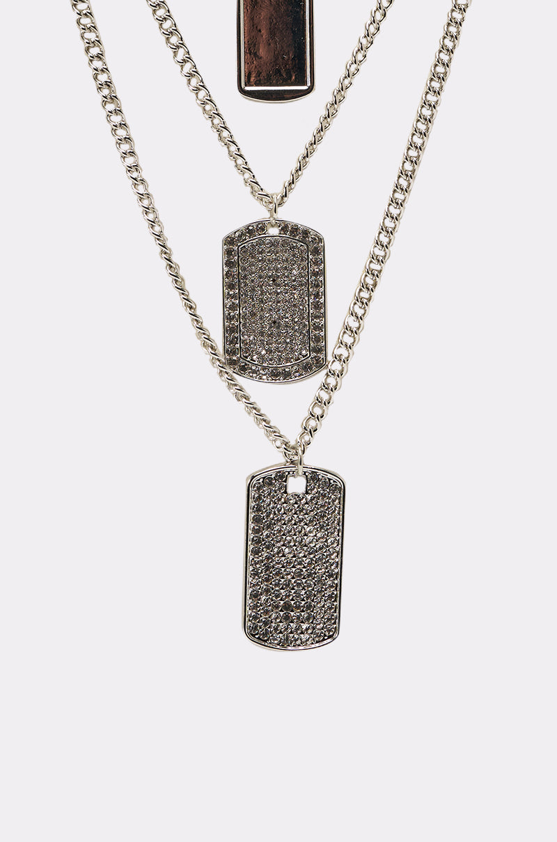 The DOG TAG BUT MAKE IT CUTE NECKLACE features three layered silver chains with a dark top tag and textured, rhinestone-accented middle and bottom tags for added sparkle. 2