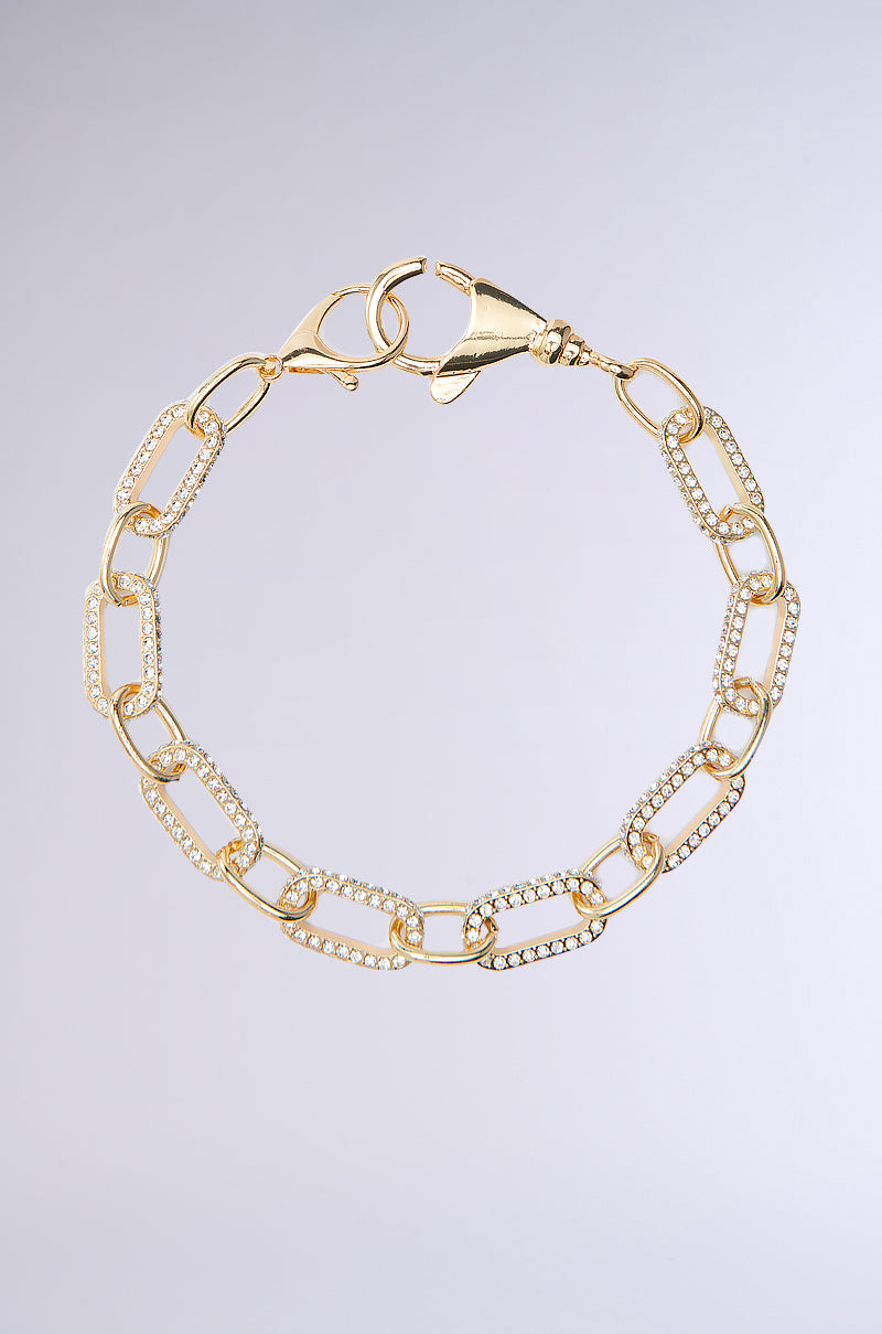 The FITS PERFECTLY NECKLACE features elongated gold links and a lobster clasp, embellished with small sparkling stones from the AKIRA Label, set against a plain light gray background.