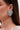 Close-up of a person wearing the ALL MY HEART EARRING IN SILVER—a large, heart-shaped rhinestone earring with a textured jeweled surface on the left ear. This sparkling piece is perfect as a bridal accessory and stands out against straight brown hair.