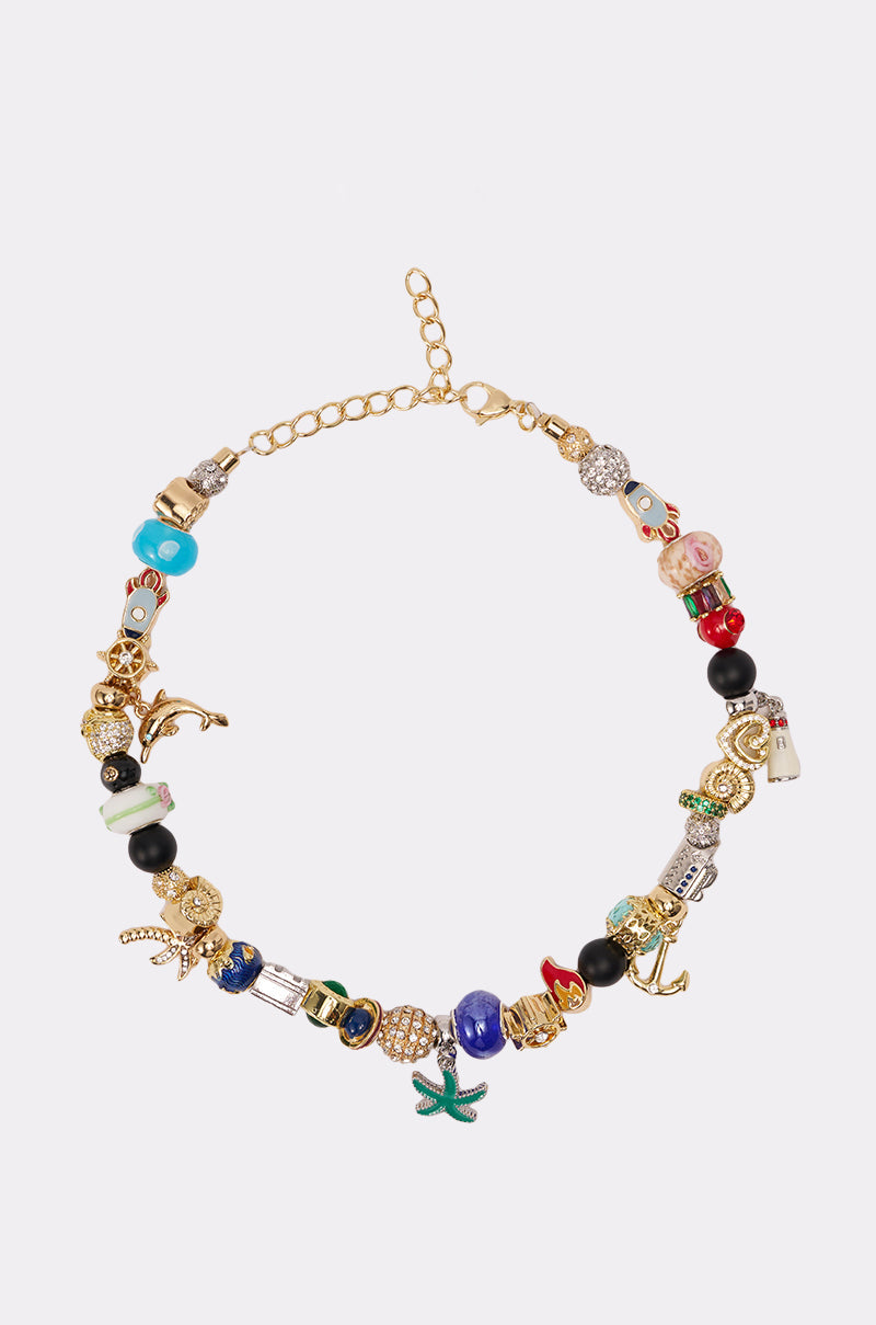 The THIS AND THAT NECKLACE is a gold-tone choker adorned with whimsical charms, vibrant beads, gemstones, and playful shapes like a starfish, anchor, and animals—displayed on a simple light background. 0