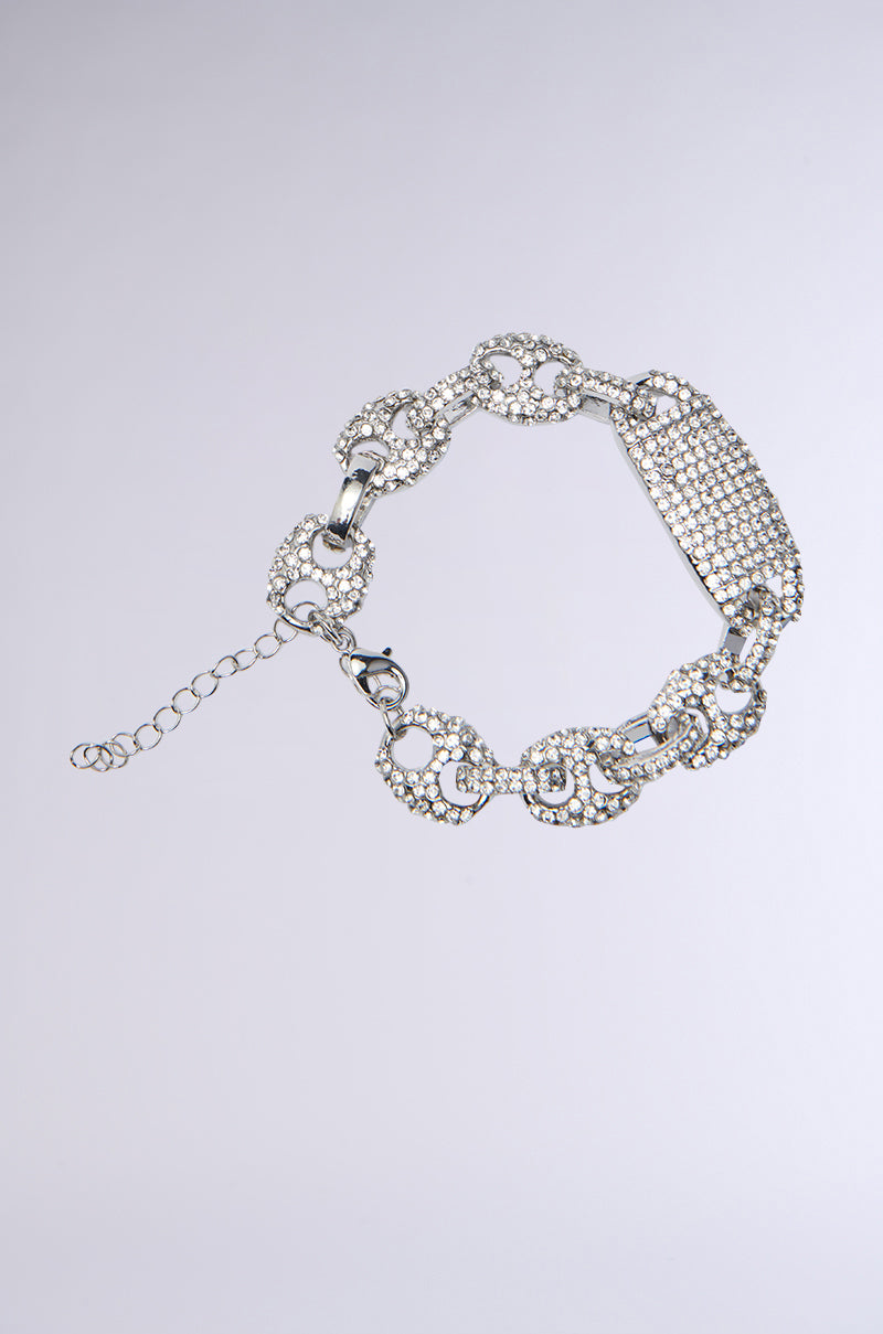 Discover the MY COLLECTION ICED OUT BRACELET: a silver chain bracelet with large oval links adorned with sparkling crystals. It features an adjustable chain for the perfect fit and lies elegantly against a light gray background.