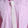 The PEARLY TIE shirt features pink and white stripes with faux pearl beads and a textured necktie silhouette, showcasing an elegant design against a plain background.