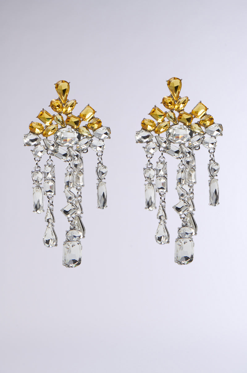 Introducing the QUEEN SH* EARRING: elegant chandelier earrings featuring clear and yellow gemstone clusters in symmetrical arrangements. With cascading chains in a dangle silhouette, these earrings showcase variously shaped stones for a dazzling look against plain backgrounds.