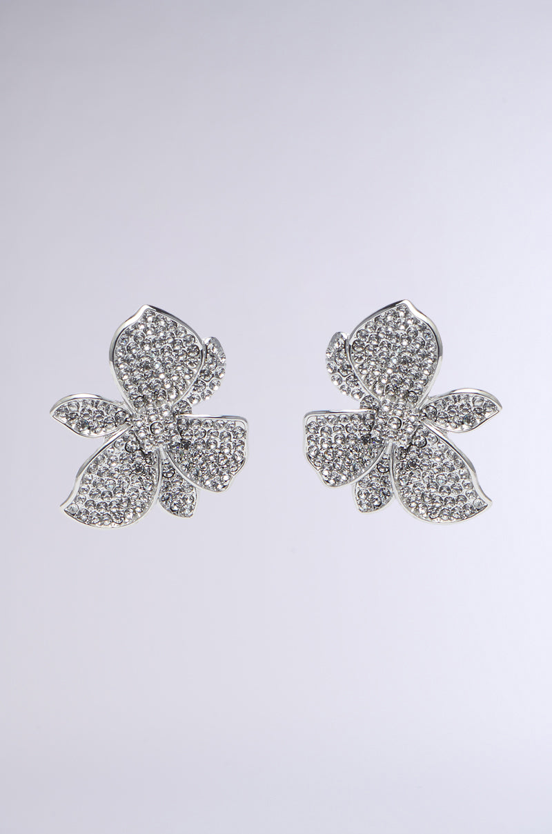 Discover the FLORAL DREAM EARRING: delicate flower-shaped pendants adorned with shimmering rhinestones, elegantly displayed on a simple gray background.