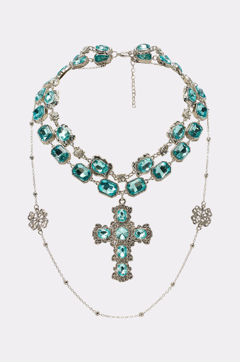 The REALLY WITH IT LAYERED NECKLACE features delicate silver chains, large turquoise gemstones, and a bold turquoise cross pendant with floral designs—a stunning statement piece for any evening look. 0