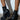 Someone stands on a concrete floor against a white wall, wearing AKI BLACK STRETCH PU CHUNKY BOOTIES. These vegan leather booties have thick platform soles and front zippers. The person's legs up to the knee cast shadows on the wall.