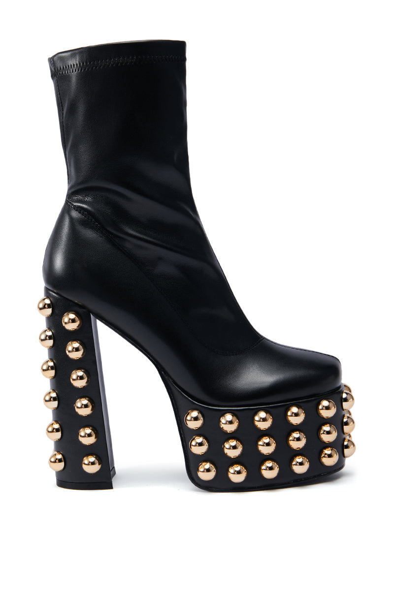 The AZALEA WANG AKITO CHUNKY BOOTIE is a stylish black chunky bootie featuring a thick platform and sturdy heel, embellished with several rows of small gold studs. Its faux leather finish enhances its elegance.