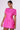 A person models the Luxon Group Inc PRETTY IN PINK BROCADE BEADED MINI DRESS, a short and vibrant pink dress embellished with a delicate, glittering floral and metallic brocade pattern. Their dark hair is styled back, complemented by dangling earrings. The dress features short sleeves and a fitted design, creating a chic and elegant look.