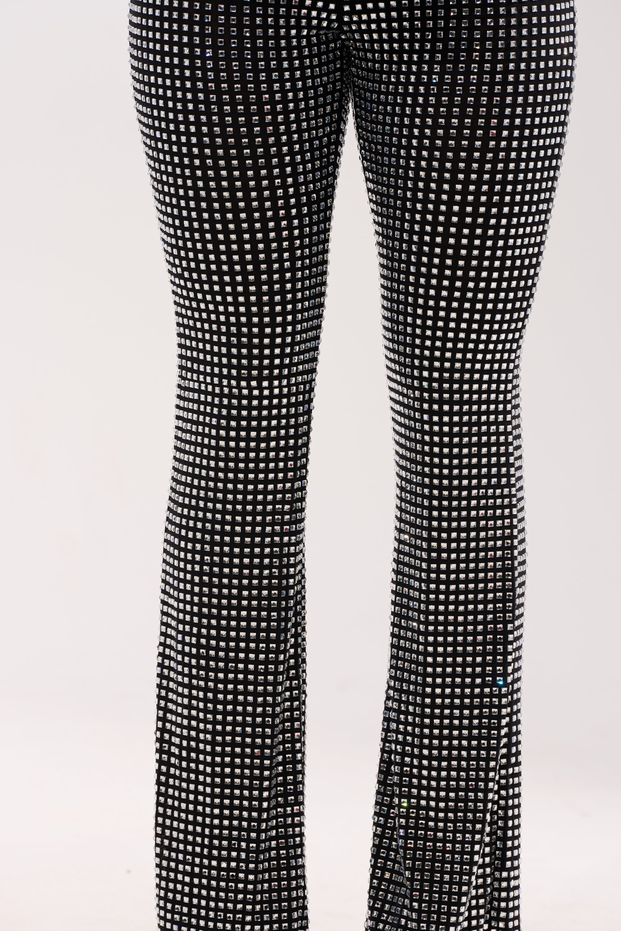 Someone stands upright wearing the ALL EYES ON ME RHINESTONE FLARE TROUSER. Only their legs and part of their waist are shown against a plain light background. 7