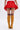 A person faces away from the camera, wearing the JANEY MICRO MINI RUFFLE SKIRT IN RED and mustard yellow thigh-high boots with brown tops, set against a plain light background.