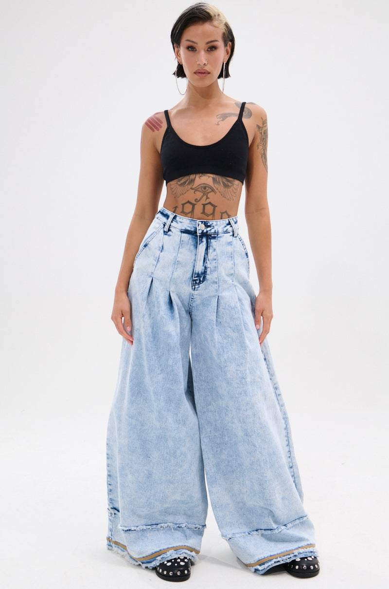 A tattooed woman wears the IN CHARGE WIDE LEG DENIM PANT and a black crop top, standing facing forward against a plain white background, hands by her sides, showcasing vintage-inspired style with modern flair.