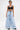 A tattooed woman wears the IN CHARGE WIDE LEG DENIM PANT and a black crop top, standing facing forward against a plain white background, hands by her sides, showcasing vintage-inspired style with modern flair.