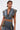 A person with wet-look short hair wears the DOWN AND DIRTY DENIM HOODED VEST in a camo print, styled as a crop top with large pockets, paired with a matching high-waisted skirt. Tattoos and a belly piercing add an edgy vibe.