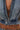 A close-up of a person wearing the DOWN AND DIRTY DENIM HOODED VEST, cropped and partially unzipped to reveal a tattoo and belly button piercing on their bare torso.
