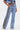 A person models ELEVATED RELAXED DENIM: high-waisted, wide-leg blue jeans with black and white floral side stripes, styled with a cropped denim jacket for a chic, modern look.