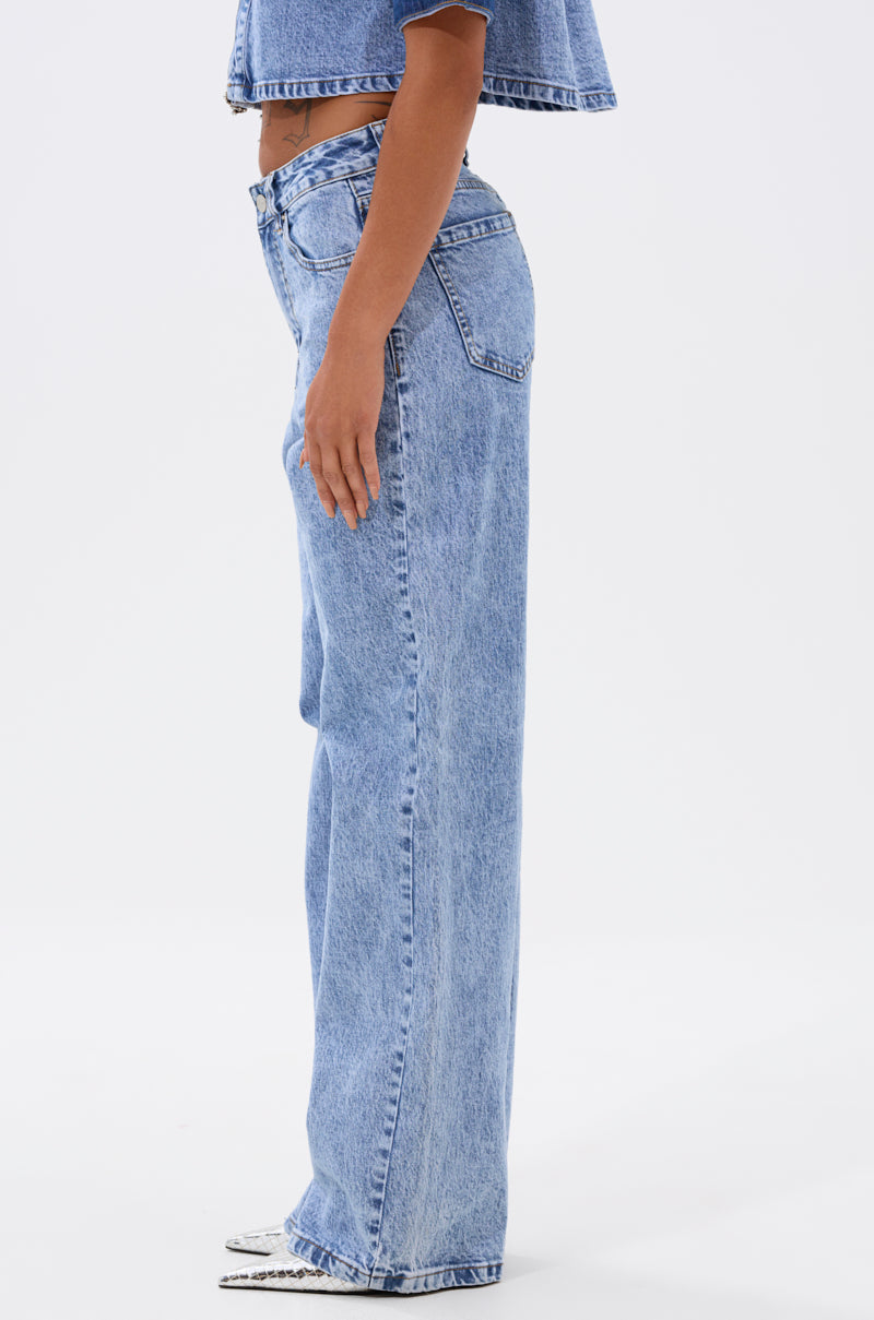 Someone models the ELEVATED RELAXED DENIM—high-waisted, loose-fitting, light-wash jeans with a matching cropped top—in profile against a plain white background. 3