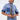 Someone is wearing the ELEVATED DENIM BUTTON DOWN with embellishments, short sleeves, dark cuffs, a patch detail, and decorative trim on the buttons, paired with matching high-waisted jeans featuring a black and white side stripe.