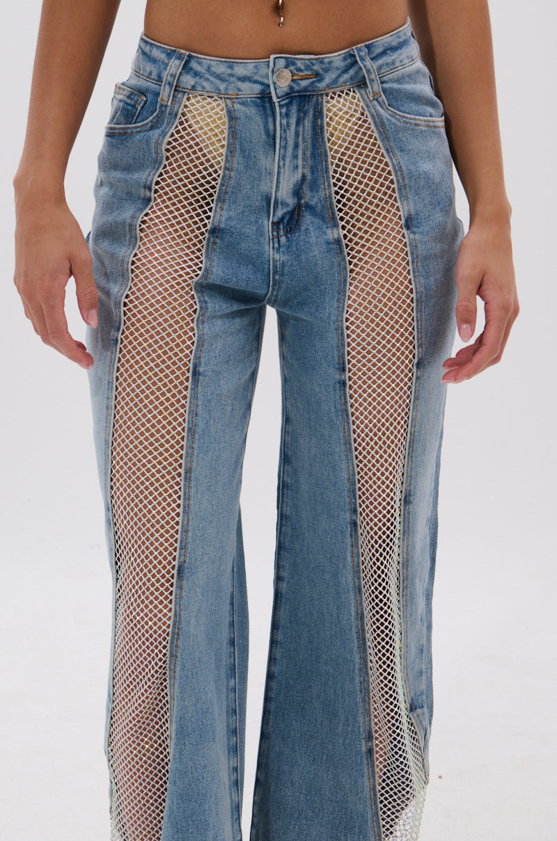 Someone wears the BLING BLING RELAXED DENIM, featuring high-rise jeans with large vertical mesh panels along the front of each leg to reveal skin. This relaxed denim has a high waist, front zipper, and classic pockets. 7