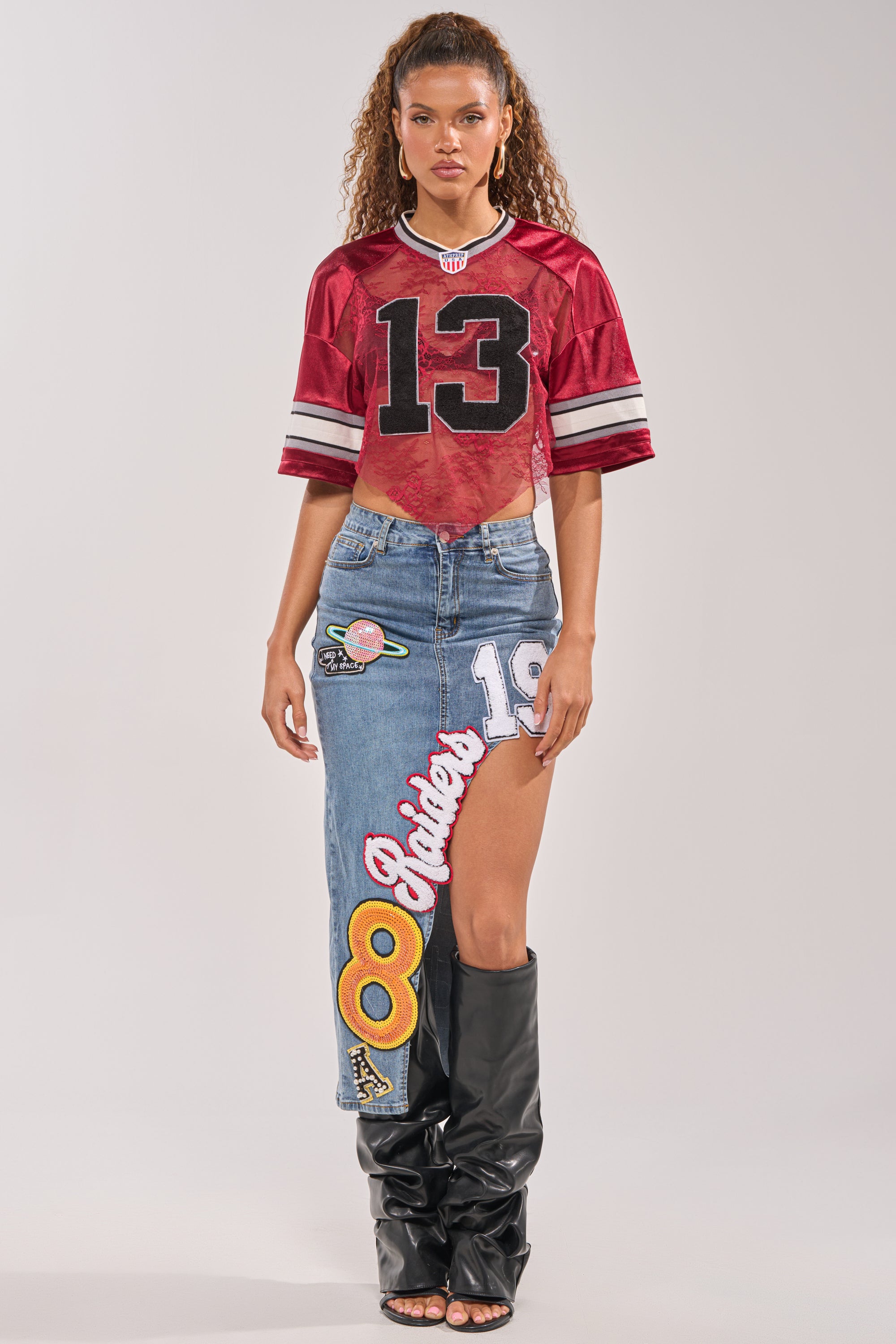 A woman stands against a light background in game day streetwear, wearing a red  5