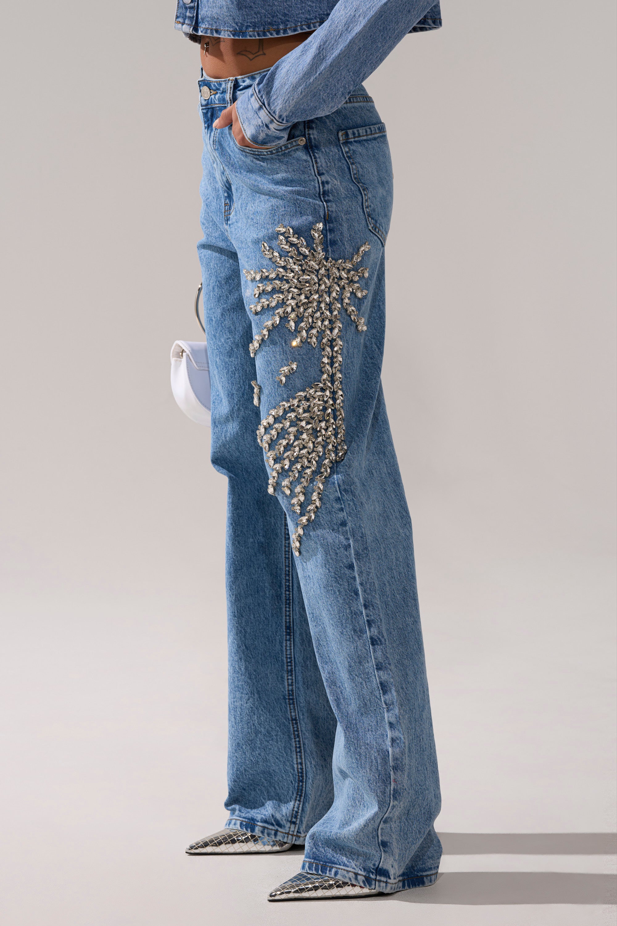 Wearing SPARKLE AND SHINE QUEEN RELAXED DENIM with rhinestone embellishment, styled with a matching denim top, pointed shoes, and a small white handbag.