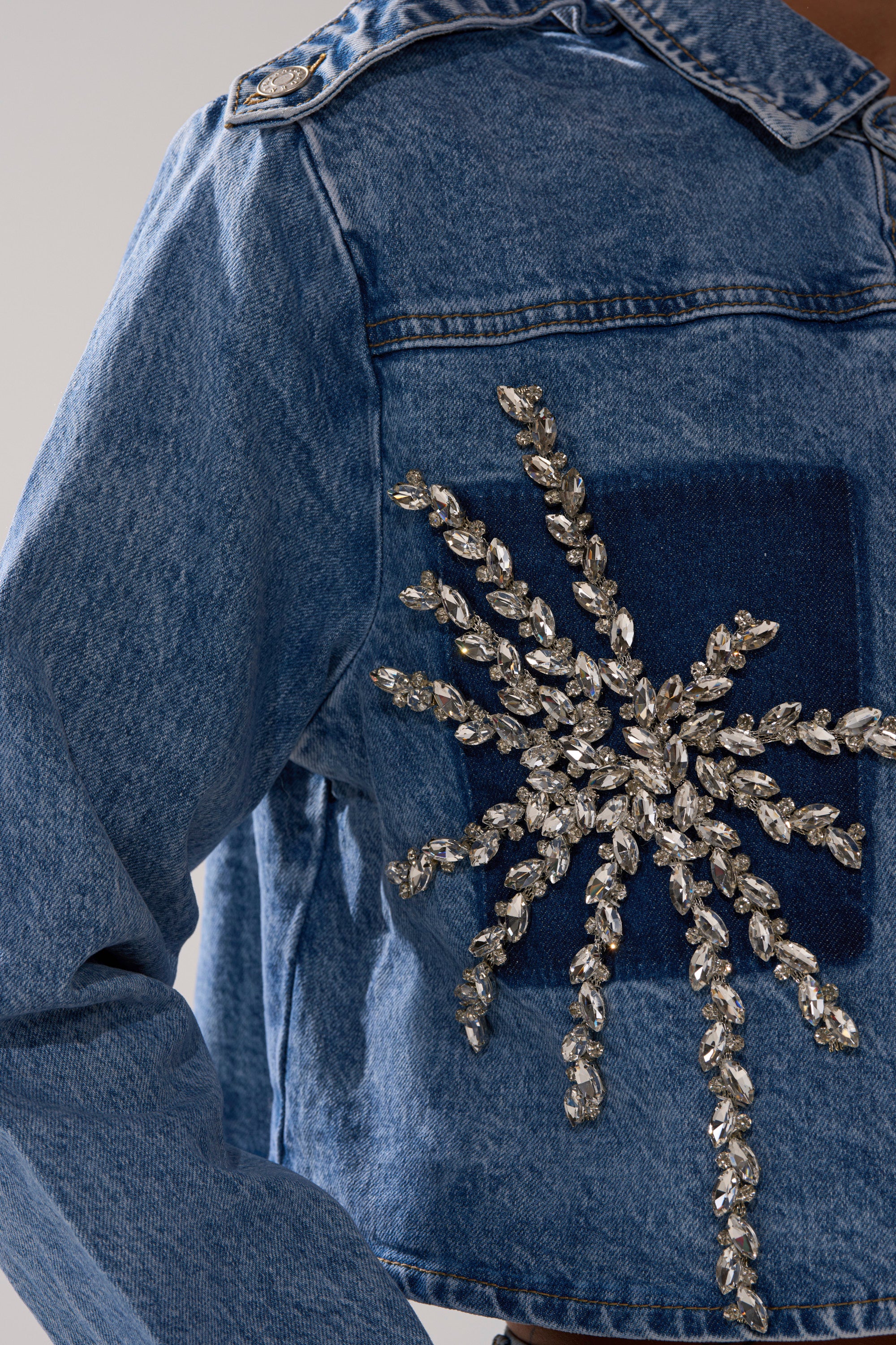 A close-up of the SPARKLE AND SHINE QUEEN DENIM BUTTON DOWN shows a large, sparkling silver crystal starburst embellishment on the front.