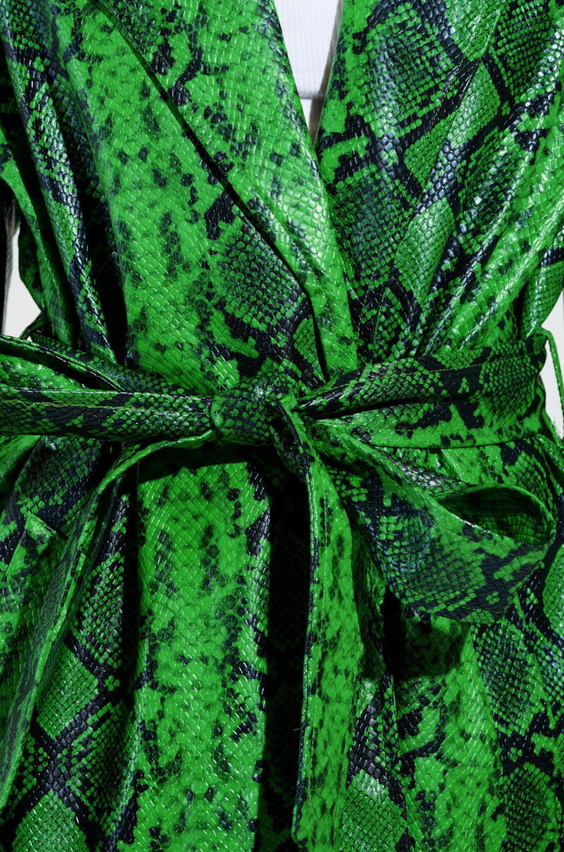 Close-up of the ENVY SNAKE PRINT TRENCH tied in a bow, featuring its vibrant green faux leather and embossed snakeskin design. The shiny texture and intricate scale pattern create a bold, eye-catching look.