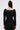 A woman with long brown hair, styled half-up, models the fitted JESSIE BANDAGE ZIP UP BLOUSE in black with vertical seams and a square neckline. She faces away from the camera, highlighting the back against a plain background.