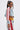 Wearing the ALL AROUND THE WORLD AGAIN DENIM JACKET, a woman with long, straight hair in a high ponytail rocks oval sunglasses and street-style flair in a cropped denim jacket with red and white striped sleeves and matching striped denim pants.