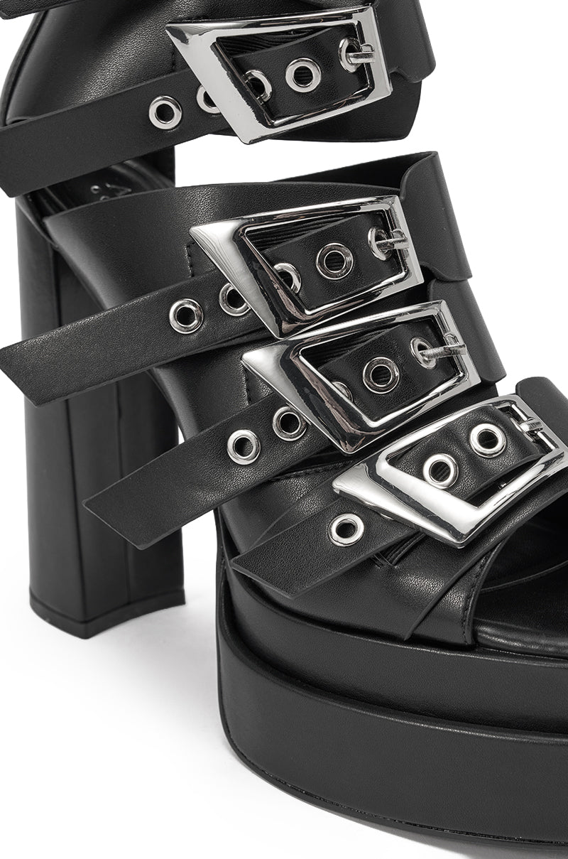 Close-up of the AKIRA GOLD ALBERIC BLACK CHUNKY PLATFORM SANDAL, a faux leather design with black block heels, wide straps, and eye-catching silver buckles and eyelets for a bold, edgy look. 5