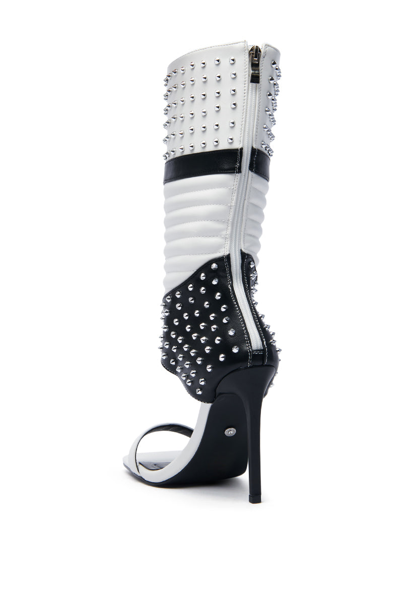 The AZALEA WANG ALBERTO Black White Studded Open Toe Boot boasts sleek faux leather with ribbed panels and silver studs. Its chic design is completed by an elegant stiletto heel and a zipper running up the back.