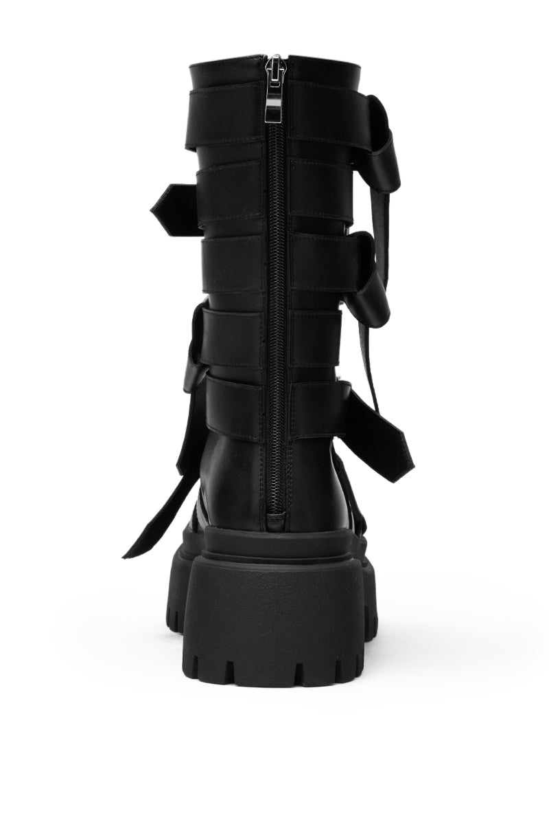 The AZALEA WANG ALCETASA Black Combat Bootie features faux leather, a central back zipper, buckle detail, wide Velcro straps, and a chunky treaded sole, shown from the back against a white background.