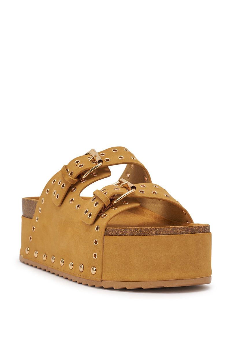 The AZALEA WANG ALGEDI TAN PLATFORM SANDAL features a mustard yellow faux suede finish, two buckled straps with grommet details, a chunky platform sole, cork-style midsole, and a ridged rubber bottom. 5