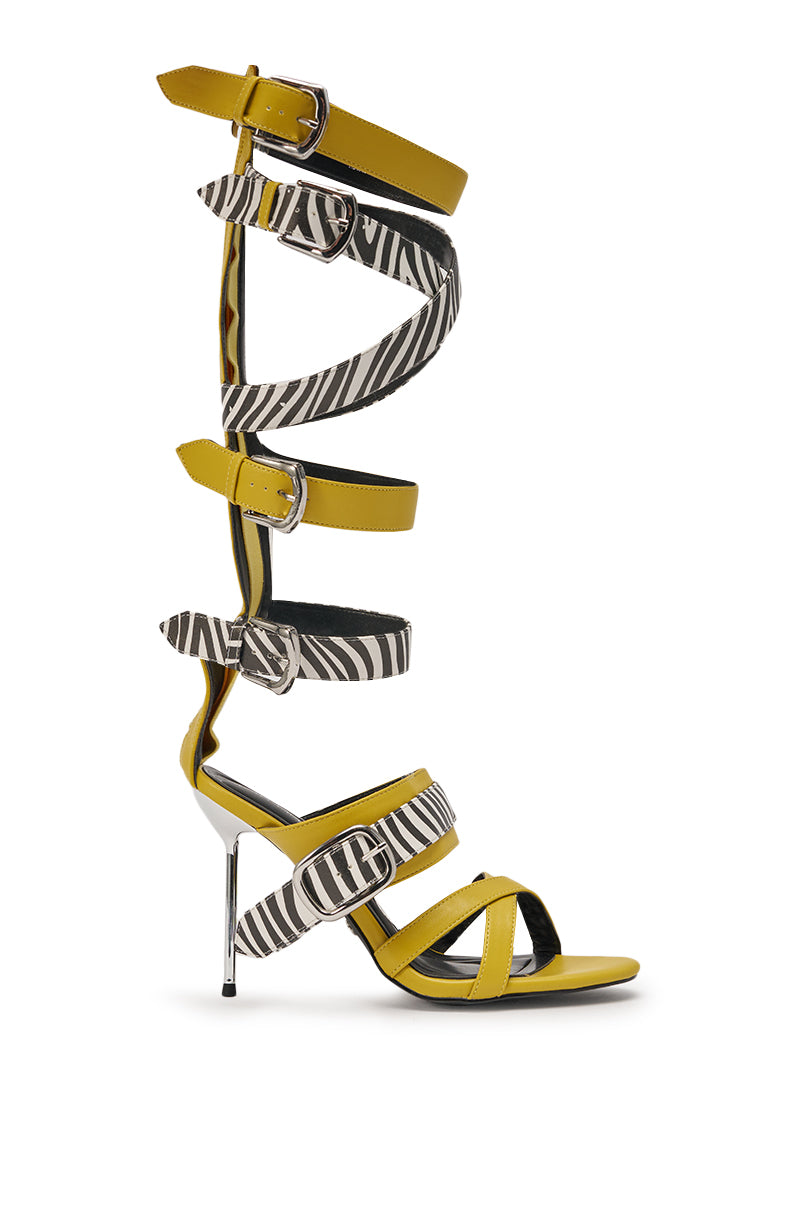 The AZALEA WANG ALIRA Mustard and Zebra Gladiator Stiletto Sandal features a thin silver heel, yellow-and-zebra print leather straps, multiple buckles, and a chic calf-high design. 3