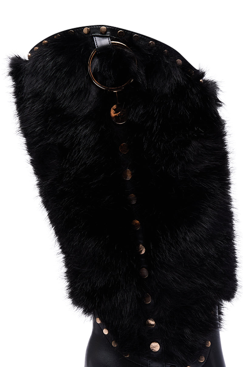 The AZALEA WANG ALISETTE BLACK FUR BOOT showcases a plush faux fur exterior, decorative metal studs, and a circular metal ring near the top, offering cozy style with the bold attitude of knee-high boots.