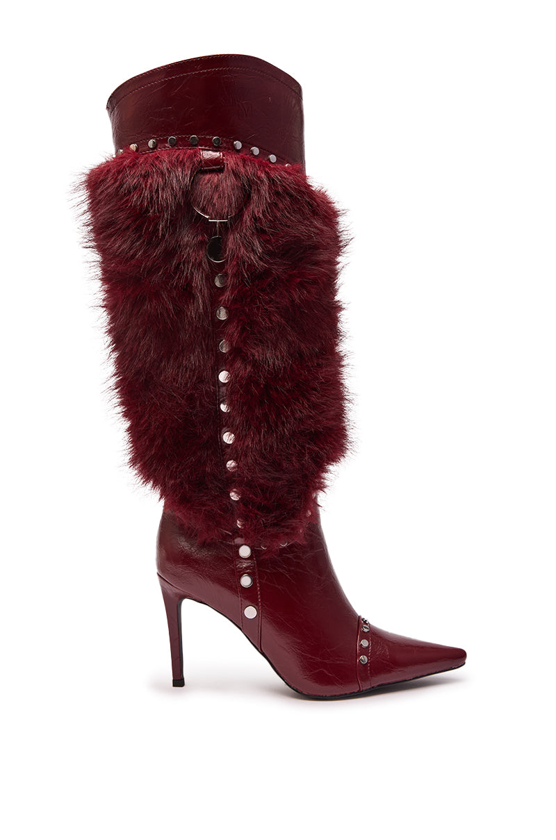 The AZALEA WANG ALISETTE Burgundy Mixed Material Fur and Snake Stiletto Boot is a knee-high pointed toe style in shiny faux leather with faux fur trim, silver studs, and a decorative side ring accent.