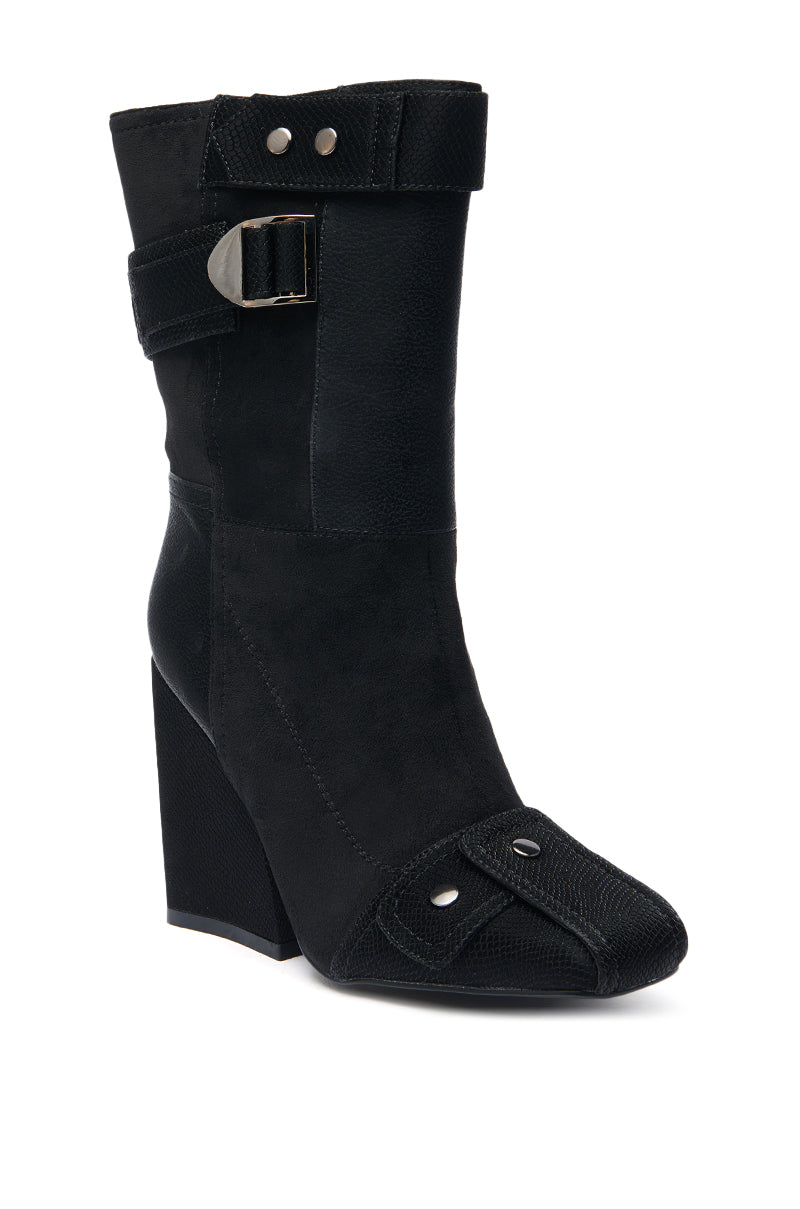 The AZALEA WANG ALLONA BLACK CHUNKY BOOTIE features a pointed toe, side buckle strap, decorative stitching, faux suede with textured accents, and metal rivet details near the front for an edgy look.
