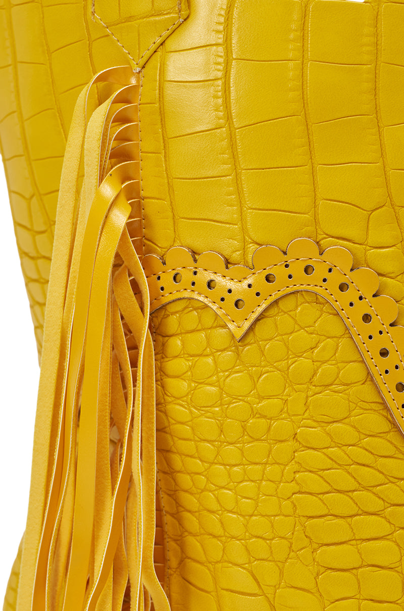 Close-up of the AZALEA WANG ALPHONSE YELLOW OPEN TOE SANDAL's crocodile-patterned material with decorative stitching, scalloped edging, and leather fringe detail, evoking western or boho-chic shoe design. 7