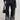 A person wearing the "THERES NO OTHER BLACK DENIM PANT" featuring a high-rise, wide-leg silhouette and a black leather jacket holds a sleek black bag. The ensemble is completed with stylish black platform shoes as the person stands against a light gray background.