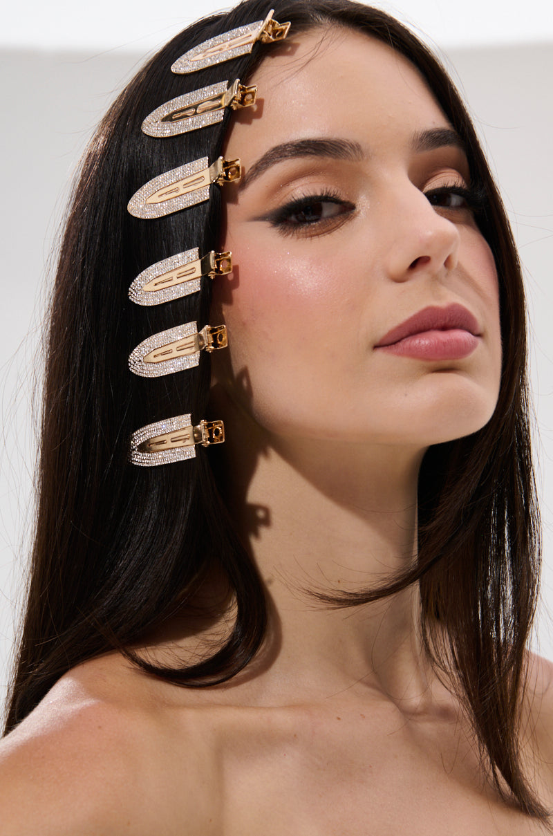 A woman with long, straight dark hair wears TOO PRETTY FOR THIS BLING HAIR CLIPS in a neat row along the side of her head. She has natural makeup, a confident expression, and stands against a plain light background.