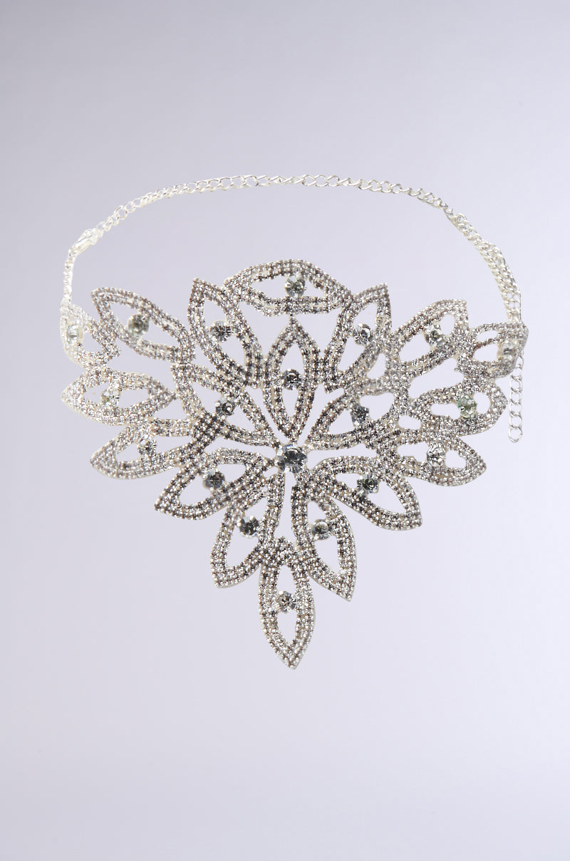 The MY LIFE IS ART CHOKER features a silver chain with an eye-catching rhinestone floral design and adjustable closure, highlighted by a large, intricate flower-shaped centerpiece on a plain light gray background.
