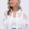A pretty lady with long, wavy gray hair wears a sheer white floral blouse over a white top and blue jeans. She accessorizes with PRETTY LADY EARRING—flower-shaped earrings with rhinestone centers—and smiles softly to the side.