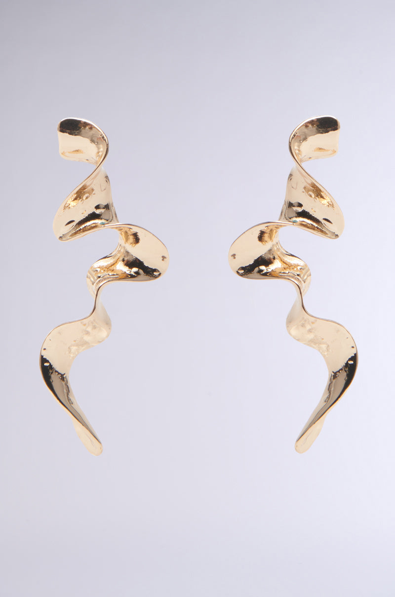 The GOLD SQUIGGLES DANGLE EARRING features a ribbon-like, twisting design with a shiny faux gold finish on a plain gray background, offering a modern and elegant abstract silhouette. 0