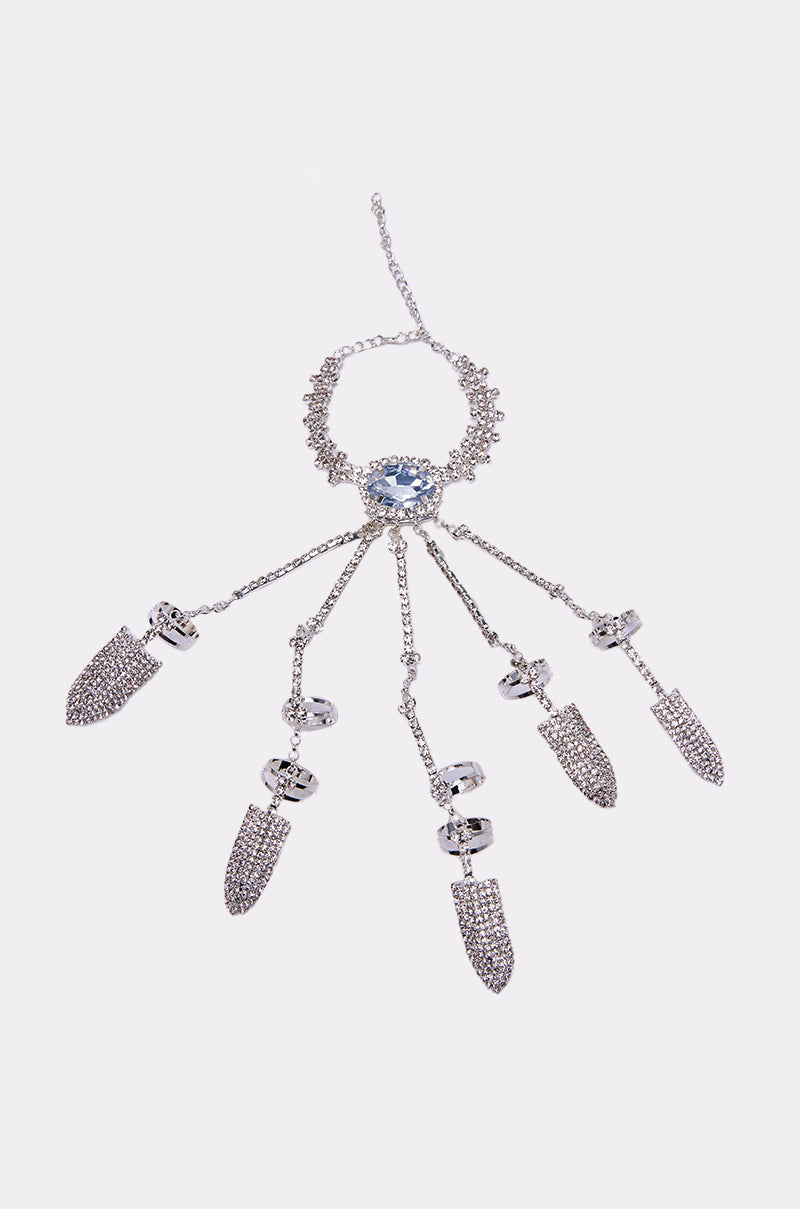 The CLAW MY WAY BLING RING SET features a decorative silver hand chain with a large central blue gem and five rhinestone-encrusted finger attachments, blending elegance and sparkle for statement jewelry lovers. 4