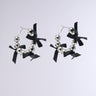 The TIE IT WITH A BOW EARRINGS are silver hoop earrings, beautifully detailed with shiny metallic and silver beads, accented by small satin black bows. Set against a simple grey background, they exude understated sophistication.