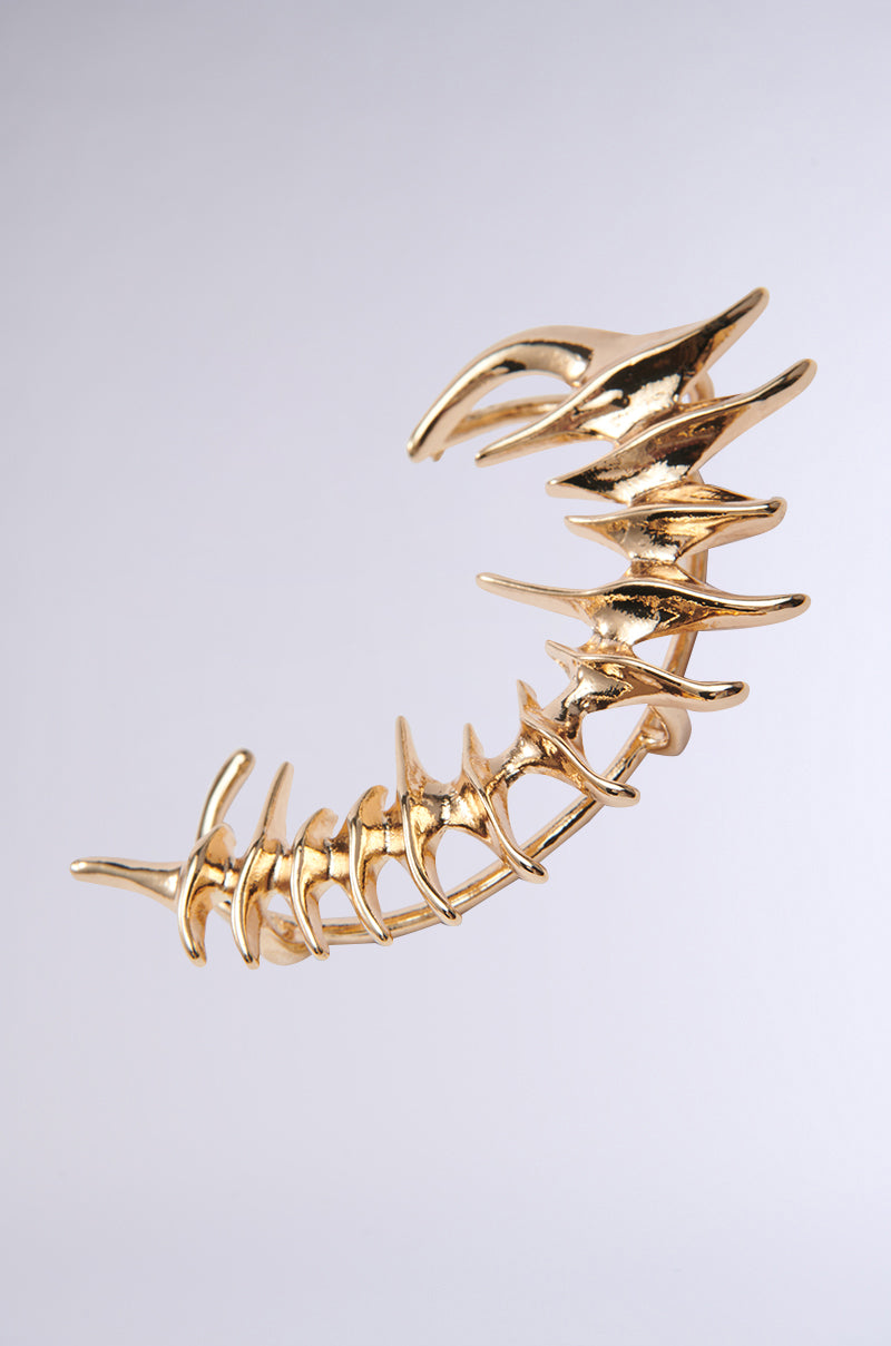 The I BOUNCE BACK EAR CUFF, featuring a faux gold and spine-shaped design with interlocking vertebrae, stands out against a light gray background as a head-turning statement accessory. 2