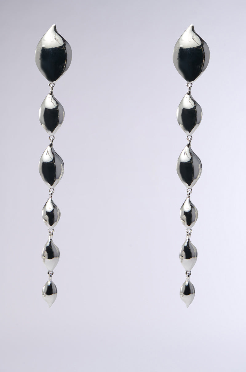 The DRIPPIN EARRING showcases shiny faux silver charms, featuring five cascading petal-shaped segments set against a plain background, offering an eye-catching and elegant design.