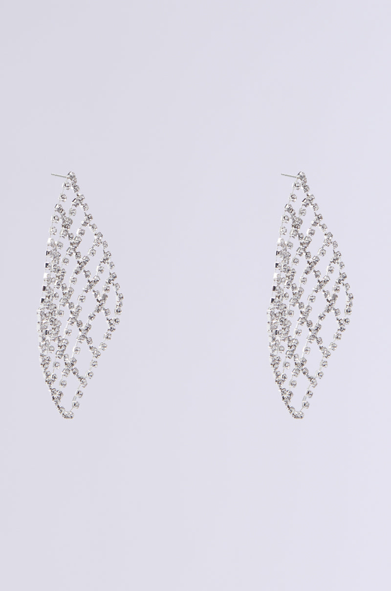 The DANCE THE NIGHT AWAY EARRINGS are diamond-shaped, dangling pieces crafted from silver with a lattice design. They feature rhinestone links adorned with small, sparkling stones in a crisscross pattern against a light grey background.