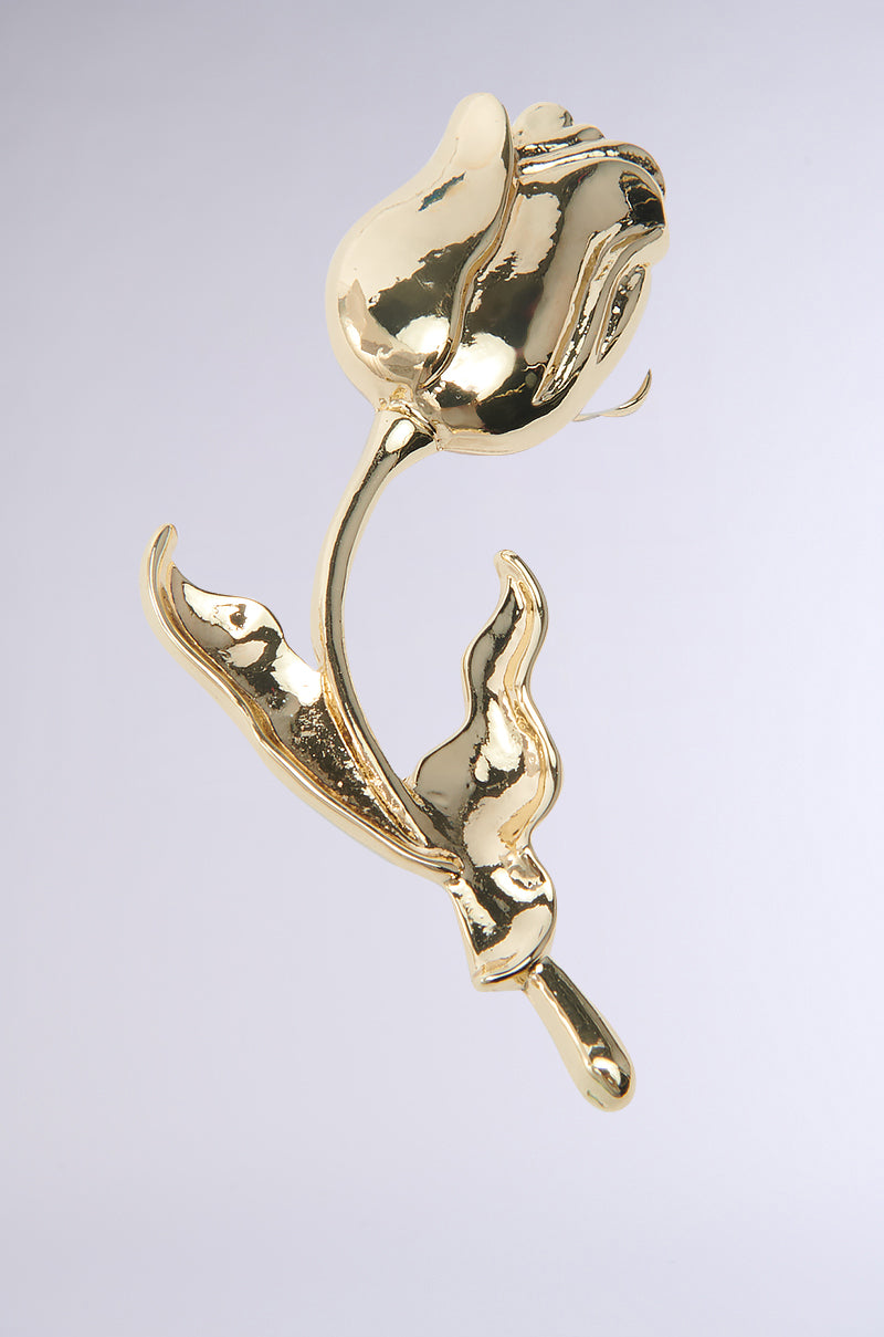 The ROSEY EARRING is a shiny metallic faux gold piece featuring a rose shape with two leaves on its stem. Set against a white background, this ear-climbing silhouette has a smooth, reflective surface that exudes luxury and elegance. 2